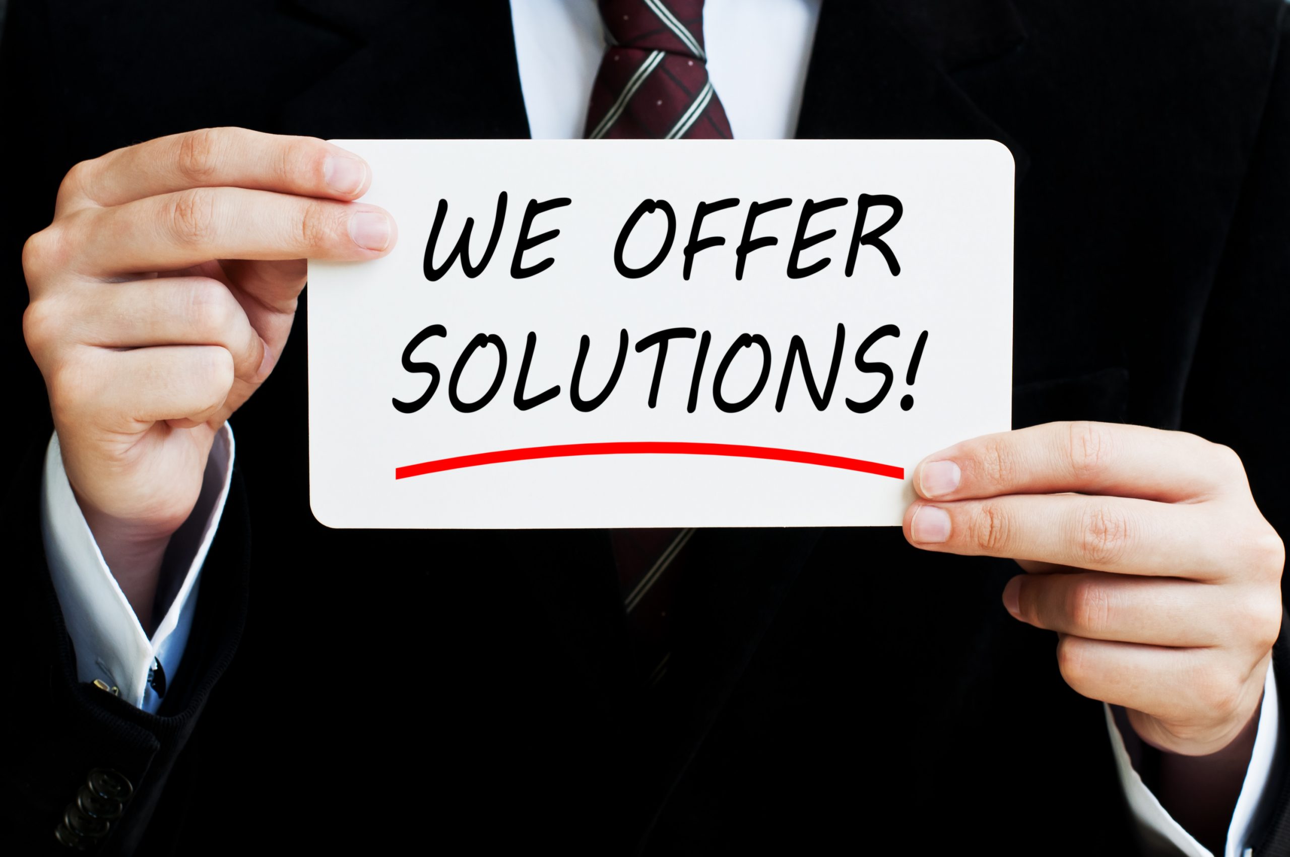a man in a suit holding a sign that says we offer solutions.