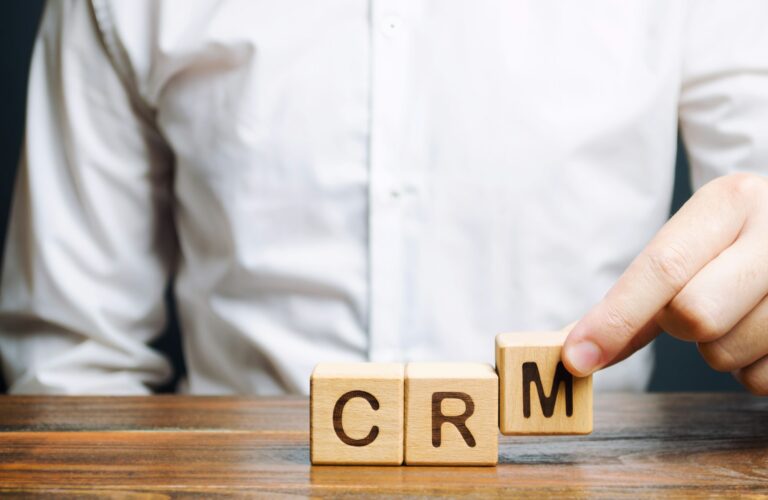 Wooden blocks with the word CRM (Customer Relationship Management) and businessman