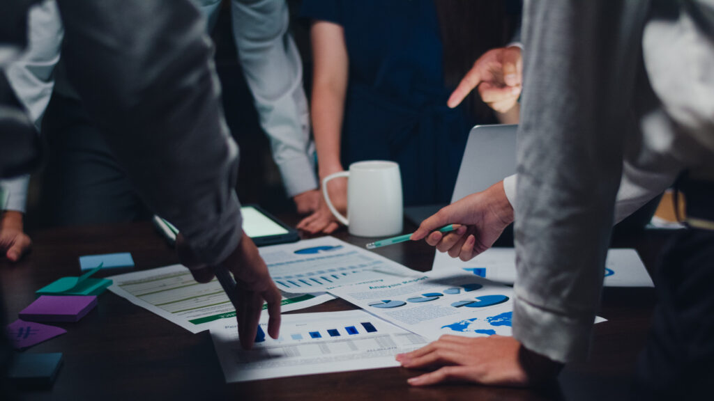 People gathered around a table analyzing charts and graphs.