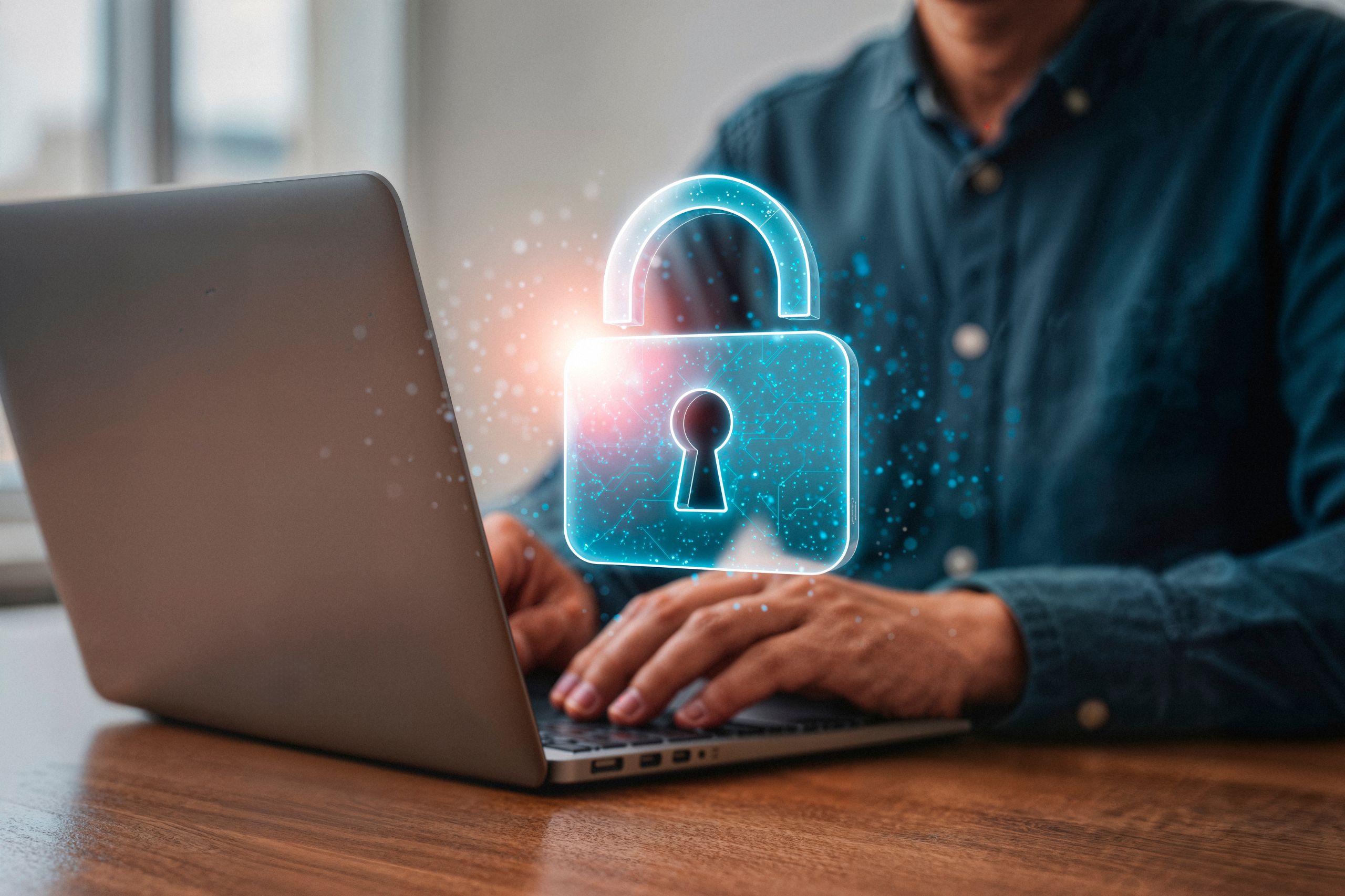 Person typing on a laptop with a glowing digital padlock icon overlay, representing affordable data protection and cybersecurity for SMEs.
