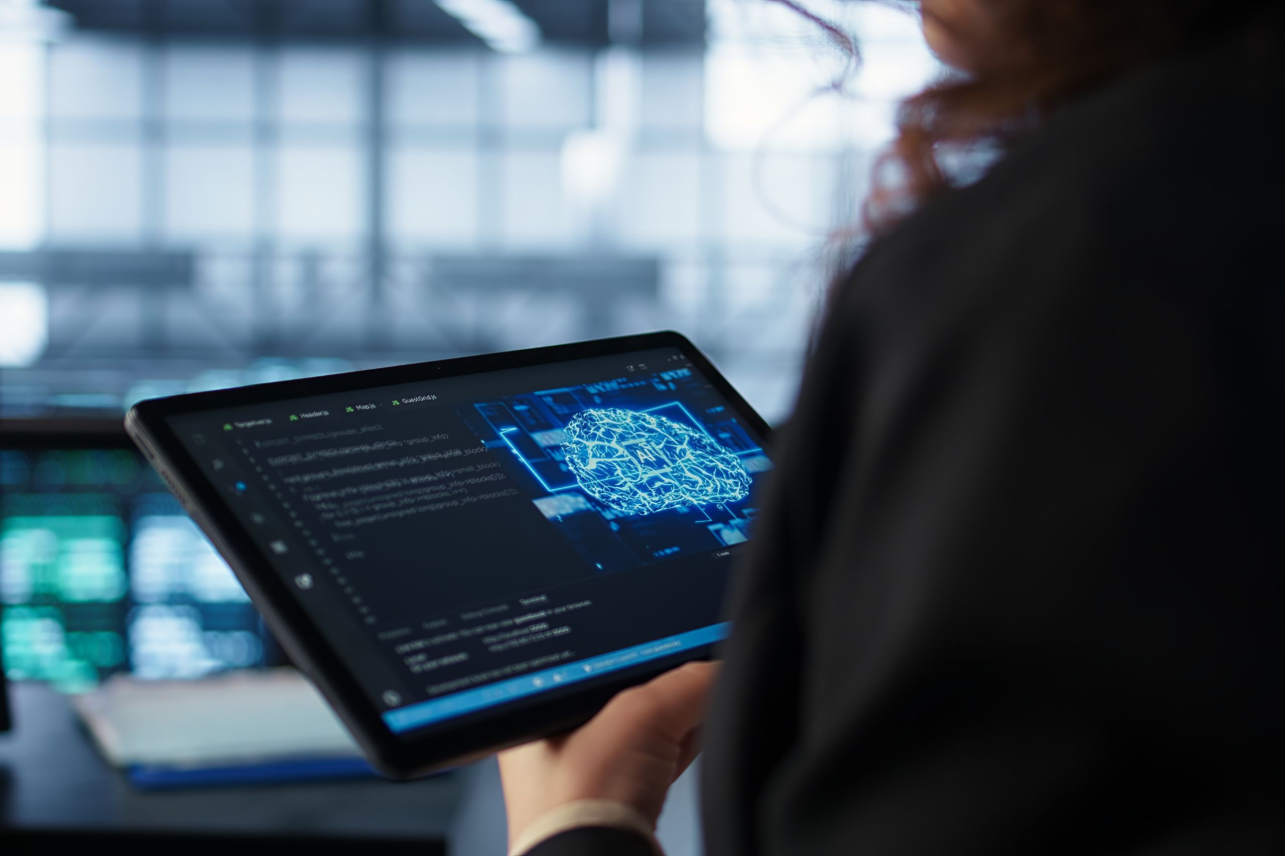 Person holding a tablet displaying lines of code and a digital circuit diagram, in a modern office or tech environment.