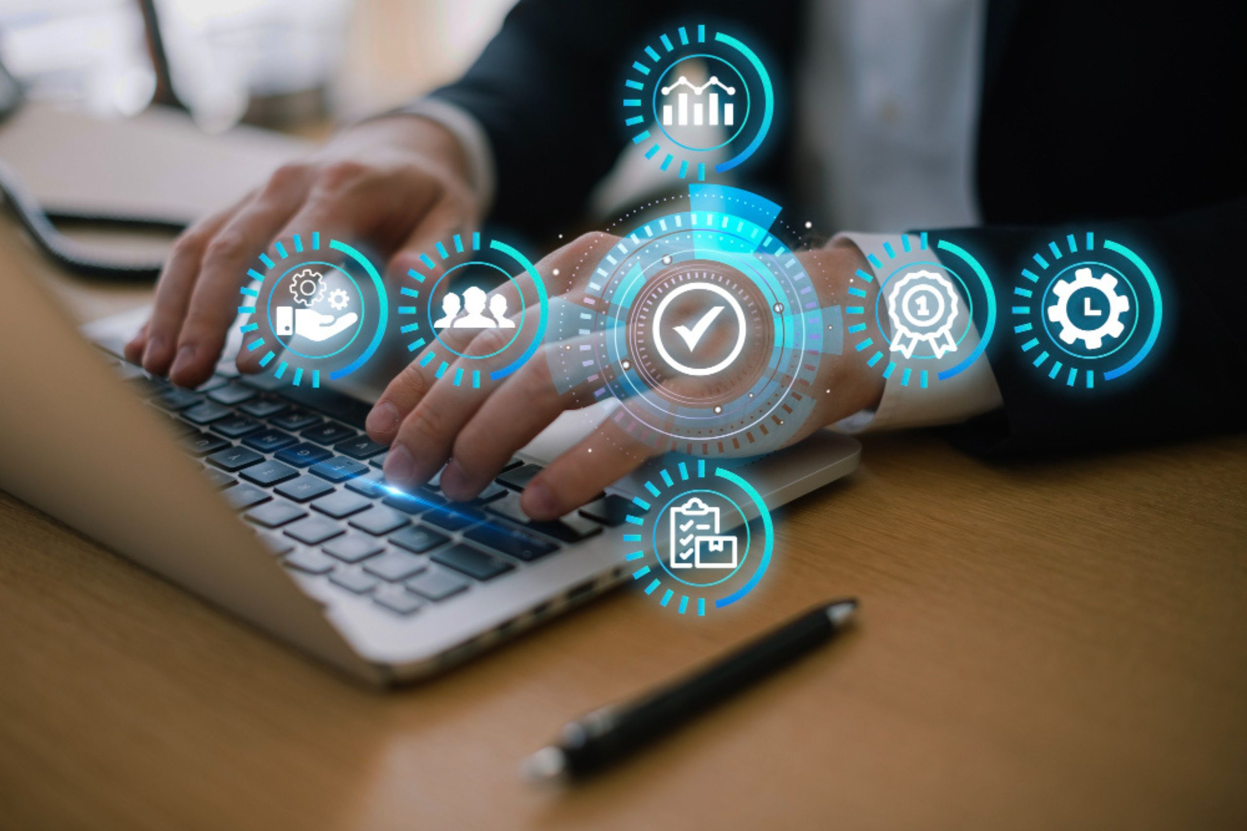 Person typing on a laptop with digital icons representing business, analytics, teamwork, and quality assurance overlaid on the image.