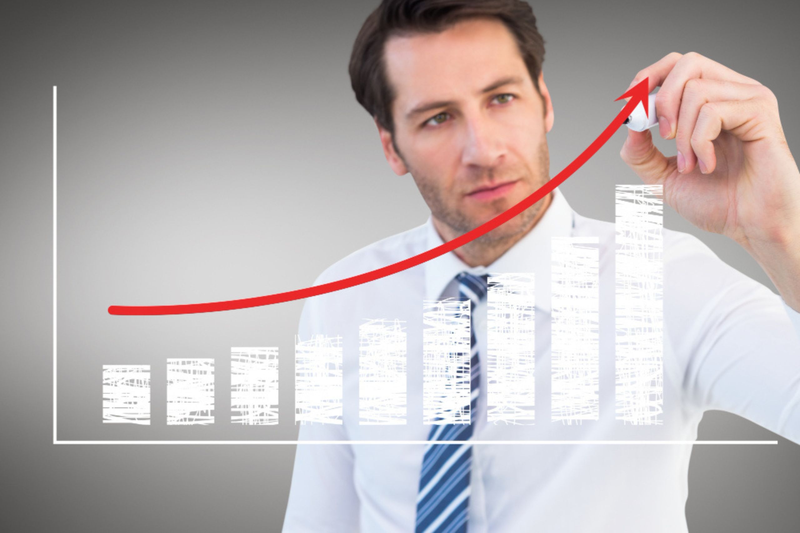 Man in business attire draws a rising red arrow on a transparent screen showing a bar graph with increasing white bars, symbolizing growth or progress.