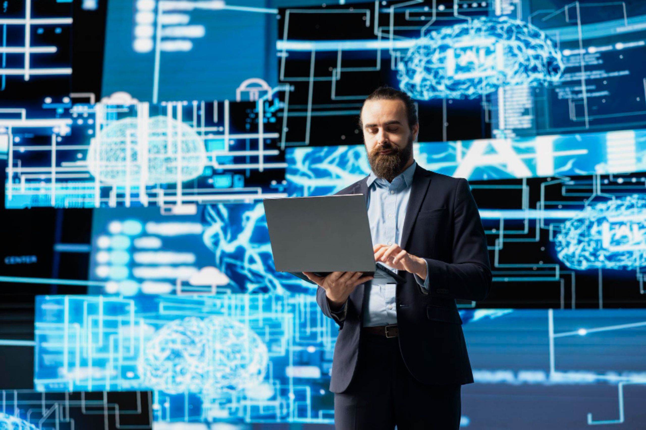 A man in a suit uses a laptop, standing in front of digital graphics showing brain images and data interfaces, suggesting artificial intelligence or advanced technology.
